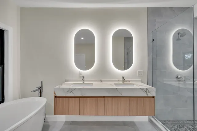 a bathroom with a double vanity sink mirror and bathtub