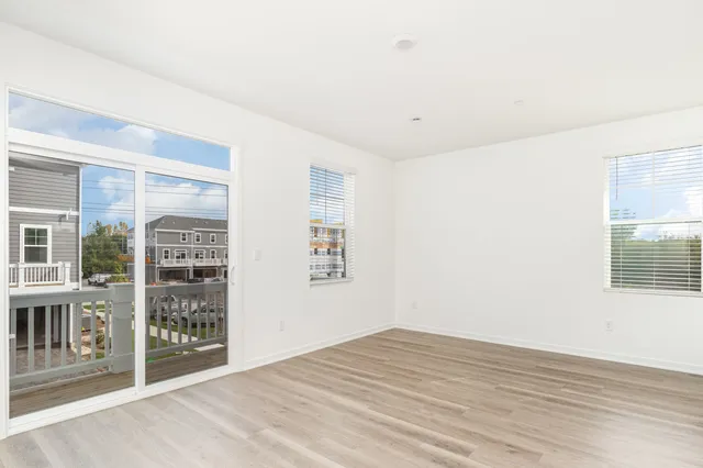 a view of an empty room with window and wooden floor