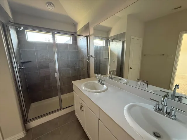 a bathroom with double vanity and a shower