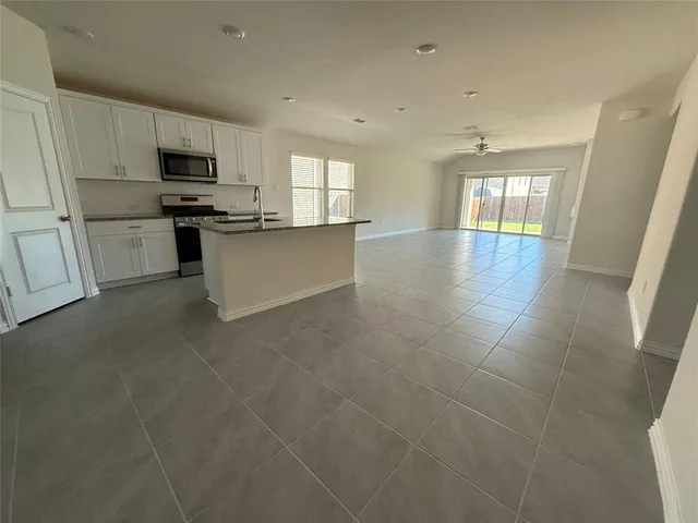 a large kitchen with white cabinets stainless steel appliances a sink and a window