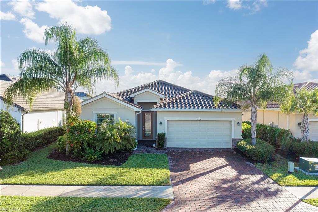 a front view of a house with a garden and palm trees