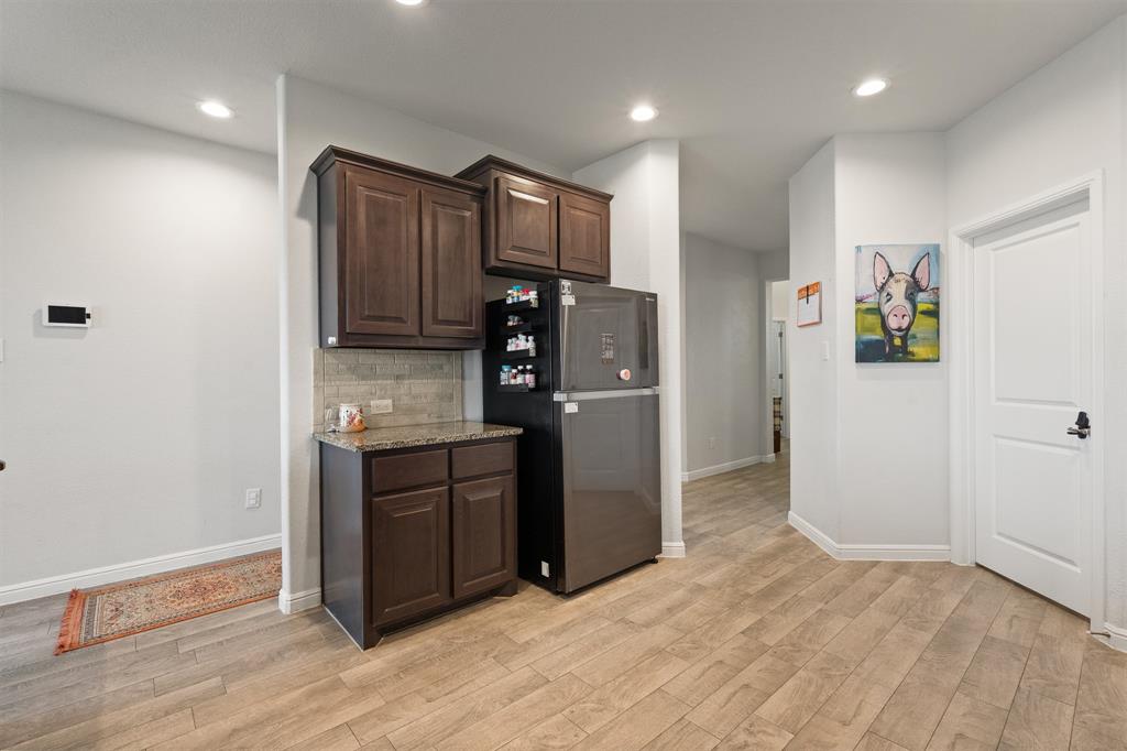 1812 Millbrae Road Cleburne, TX 76033 - Photo 5 of 30 Wood-finish flooring, recessed lighting, dark wood-finish cabinetry, light-toned backsplash, and a solid surface countertop