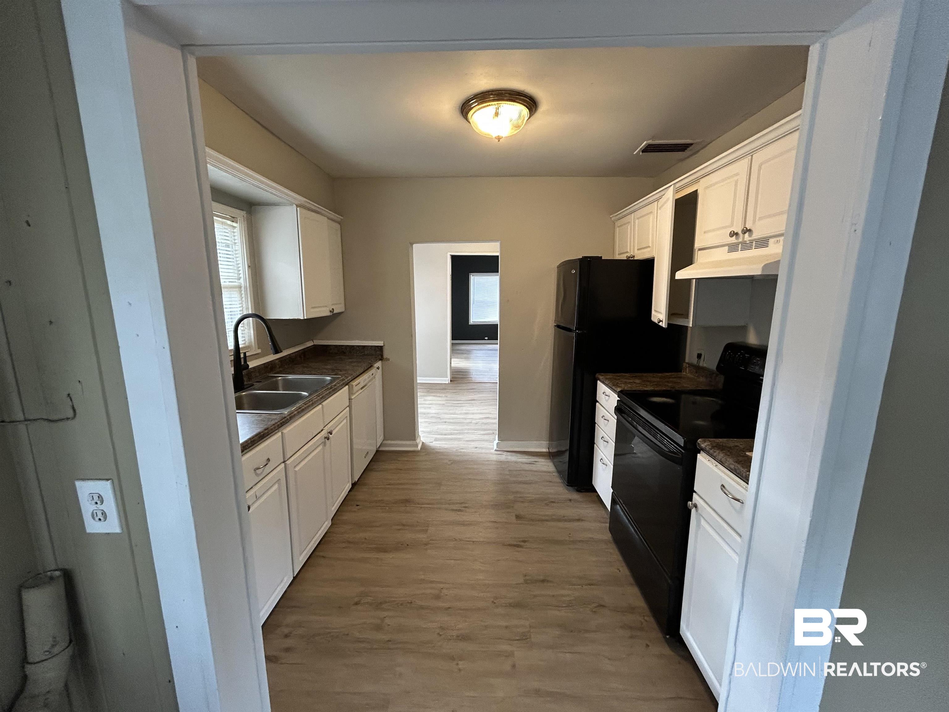 2119 Hoppin Street Mobile, AL 36605 - Photo 18 of 23 Kitchen with white dishwasher, sink, light hardwood / wood-style flooring, white cabinets, and black / electric stove