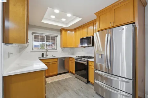 a kitchen with stainless steel appliances granite countertop a refrigerator a sink dishwasher a stove top oven a refrigerator and cabinets