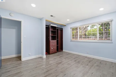 a view of an empty room with wooden floor and windows