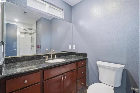 a bathroom with a granite countertop toilet sink and mirror