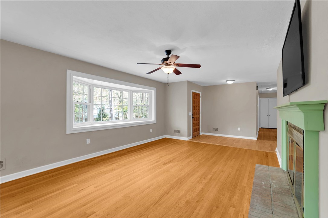 106 Mitchell Avenue Clemson, SC 29631 - Photo 5 of 31 Warm hardwood floors and a cozy fireplace create an inviting atmosphere in this sunlit living room.
