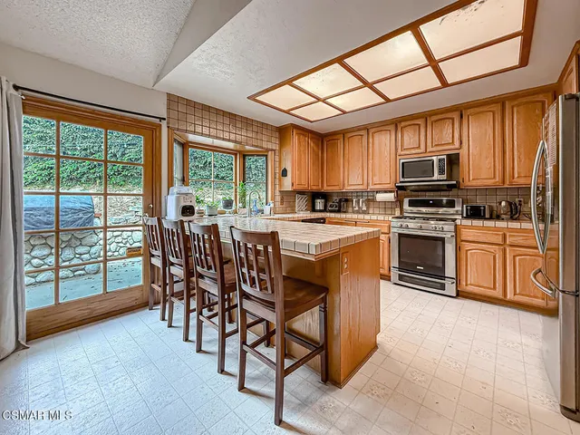 a kitchen with stainless steel appliances granite countertop a stove top oven a sink dishwasher a dining table and chairs with wooden floor