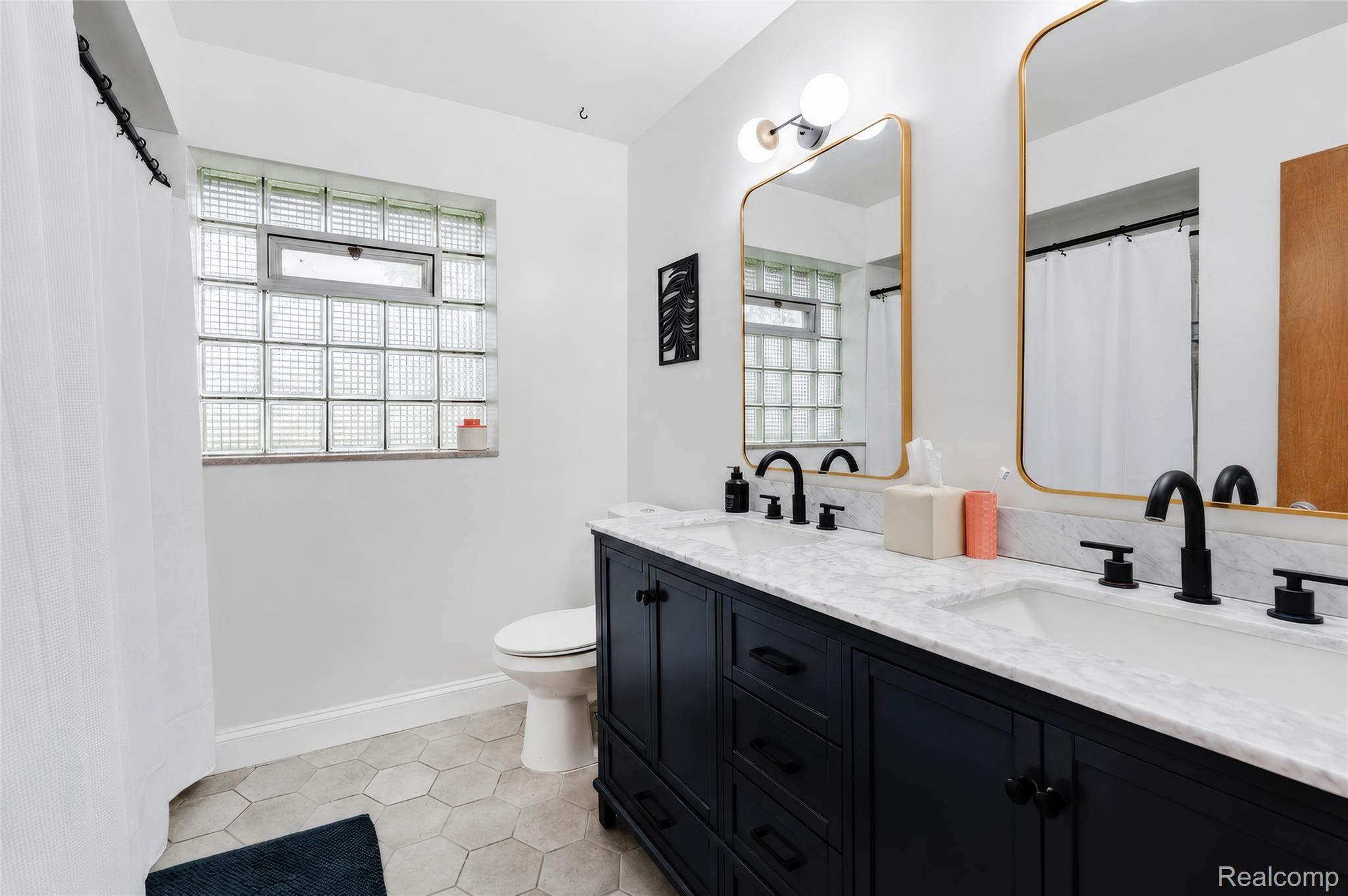 4499 South Linden Road Flint, MI 48507 - Photo 28 of 36 Dual vanity with marble-finish countertop, matte black fixtures, and gold-framed mirrors