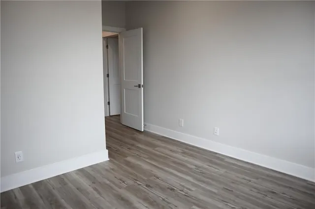 a view of an empty room with wooden floor and a ceiling fan