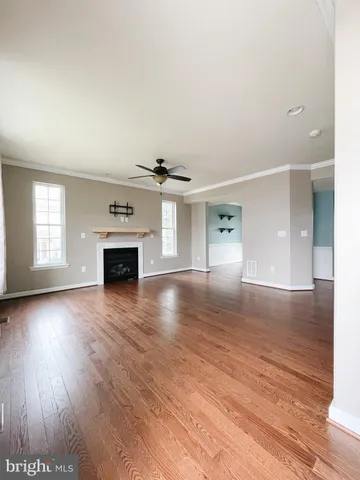 an empty room with wooden floor fireplace and windows