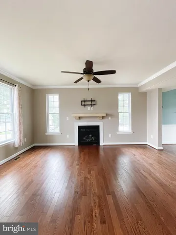 an empty room with wooden floor fireplace and windows