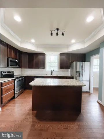 a large kitchen with stainless steel appliances wooden cabinets and a refrigerator