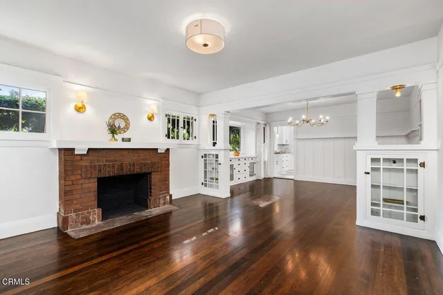a view of an empty room with wooden floor and a fireplace