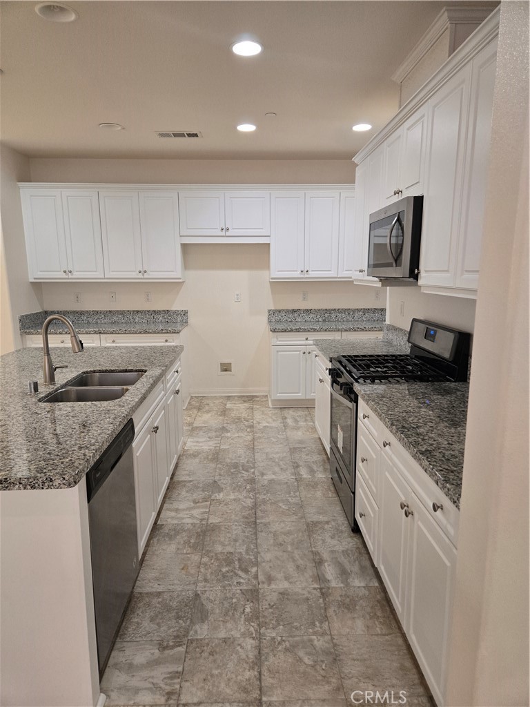 11014 Via Del Corso Riverside, CA 92505 - Photo 5 of 30 a large kitchen with stainless steel appliances granite countertop a stove top oven a sink a refrigerator and white cabinets