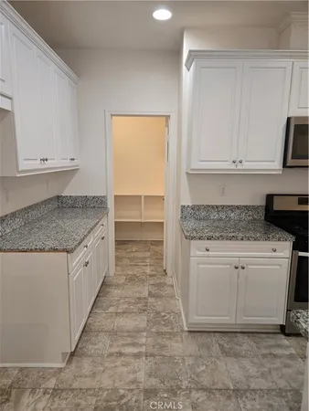 a kitchen with granite countertop white cabinets and white appliances