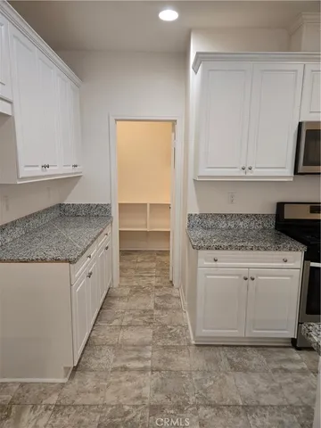 a kitchen with granite countertop white cabinets and white appliances