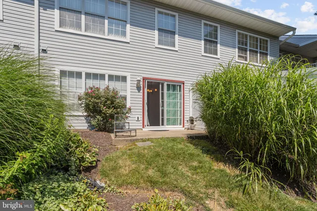 a view of a house with brick walls and a yard with plants and trees