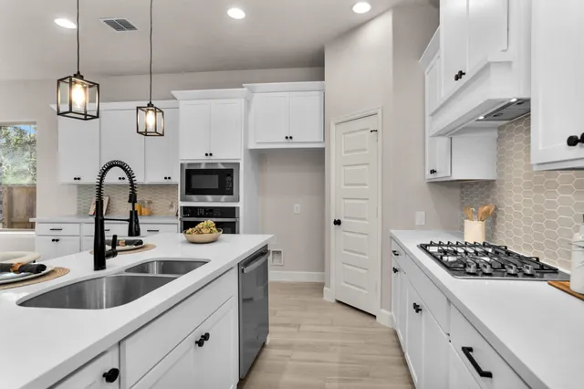 a kitchen with stainless steel appliances granite countertop a sink a stove and a refrigerator