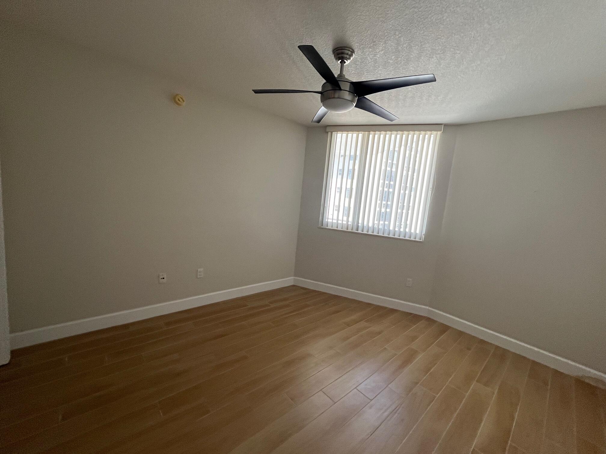 1551 North Flagler Drive, Unit 802 West Palm Beach, FL 33401 - Photo 10 of 31 an empty room with wooden floor ceiling fan and windows