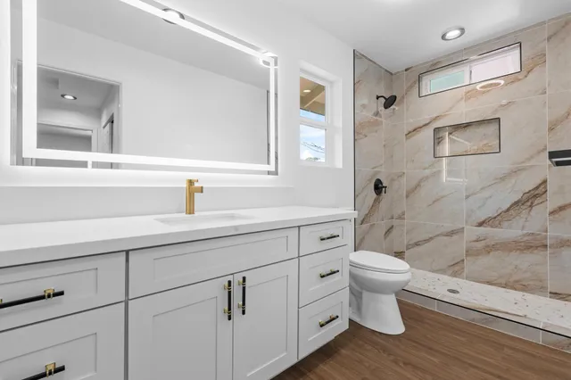 a bathroom with a sink toilet a mirror and shower