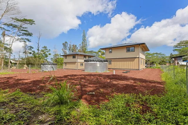 a view of a house with a yard and large trees