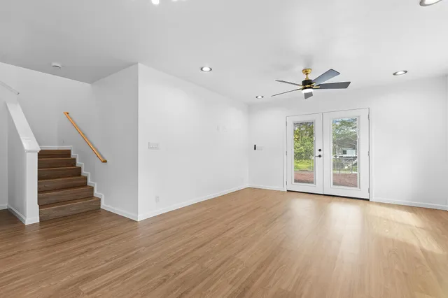 a view of an empty room with wooden floor and stairs