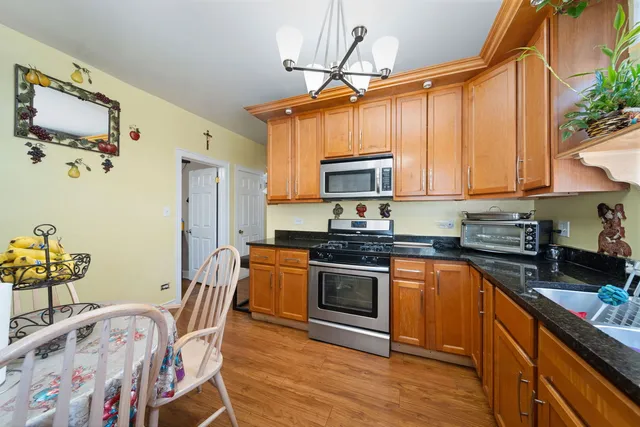 a kitchen with stainless steel appliances granite countertop a stove a sink dishwasher and cabinets with wooden floor
