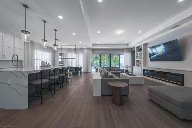 a kitchen with stainless steel appliances kitchen island granite countertop a stove a sink a refrigerator and white cabinets with wooden floor