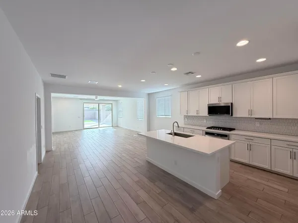 a kitchen with stainless steel appliances granite countertop a stove top oven a sink and white cabinets
