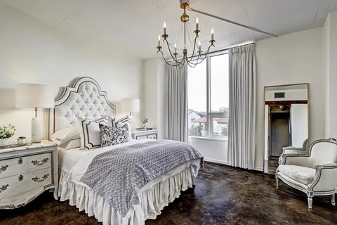 a bedroom with a bed a chandelier and dresser