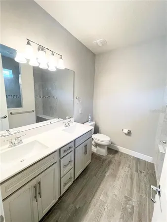 a spacious bathroom with a double vanity sink toilet and a mirror