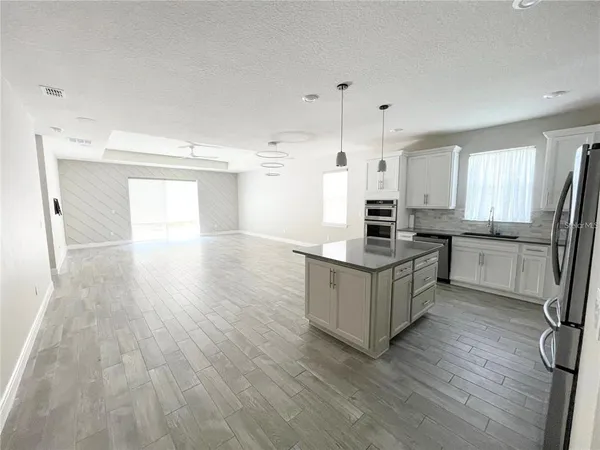 a kitchen with stainless steel appliances a stove top oven a sink dishwasher and a refrigerator with wooden floor