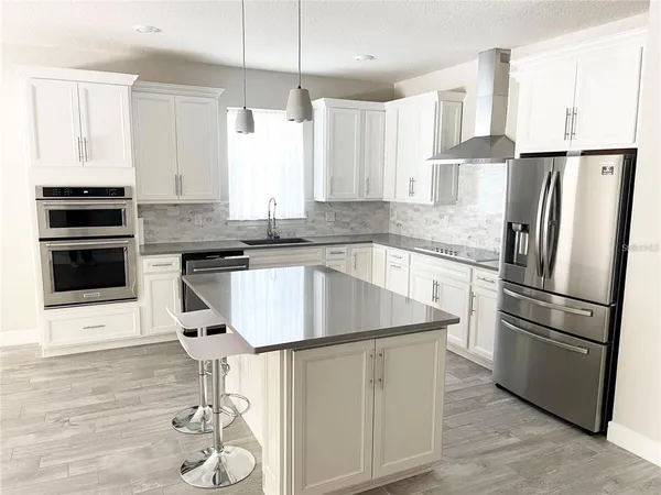 a kitchen with stainless steel appliances granite countertop a stove a refrigerator and a microwave