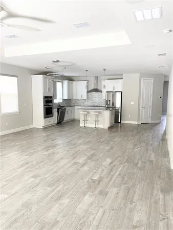 a living room with stainless steel appliances kitchen island granite countertop a sink cabinets and wooden floor