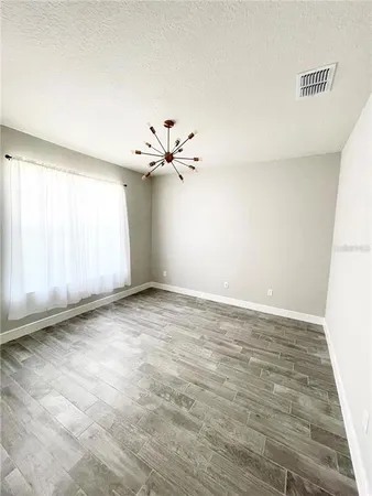 an empty room with windows and chandelier fan
