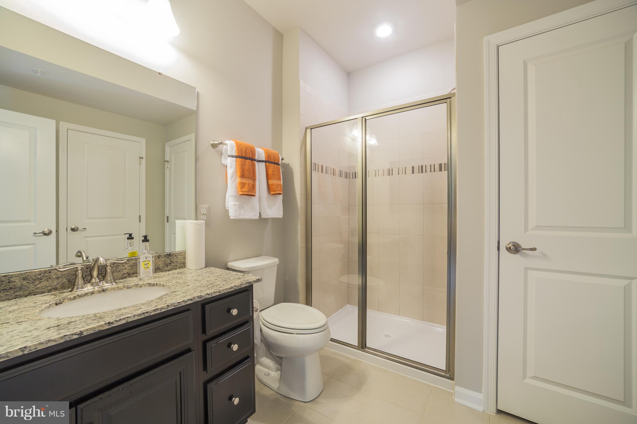 8283 Kippis Road Millersville, MD 21108 - Photo 11 of 28 a bathroom with a granite countertop sink toilet and shower