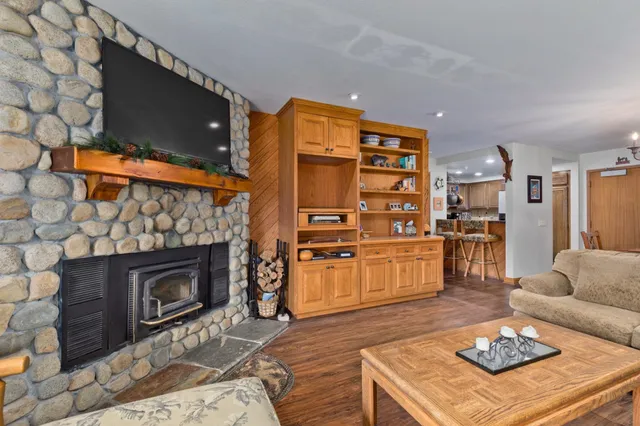 a living room with stainless steel appliances furniture a fireplace a flat screen tv and a fireplace