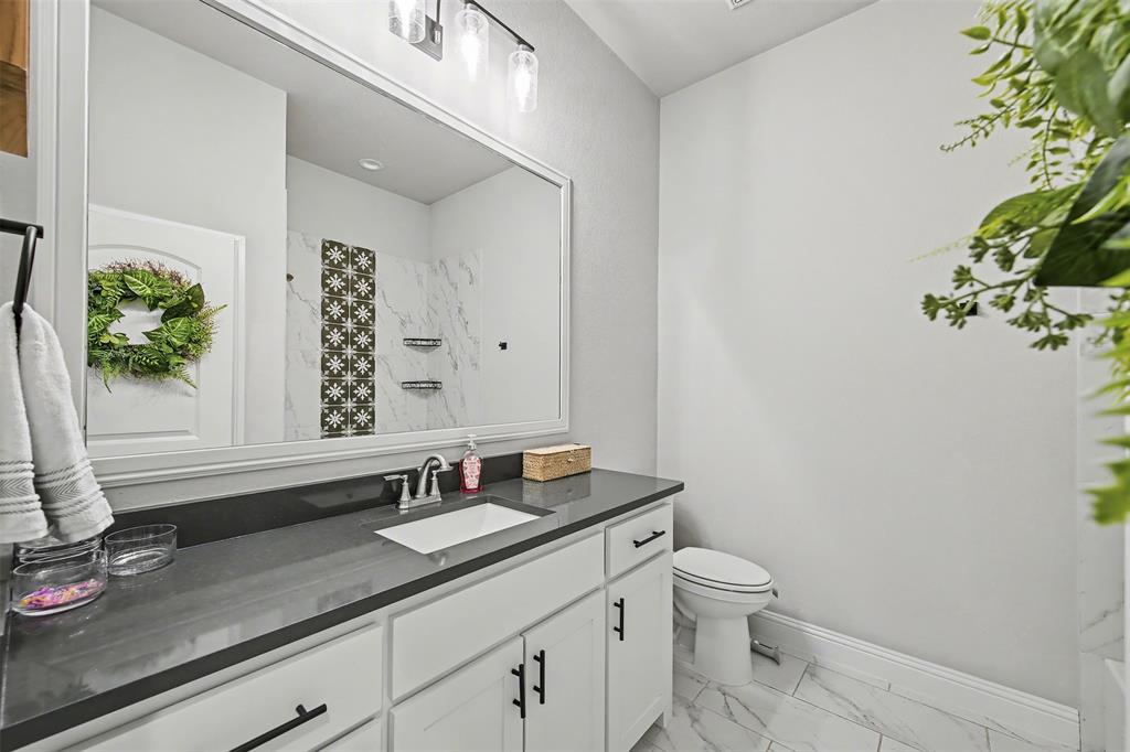 6334 Rustic Edge Street Godley, TX 76044 - Photo 20 of 26 a bathroom with a granite countertop sink a toilet and a mirror