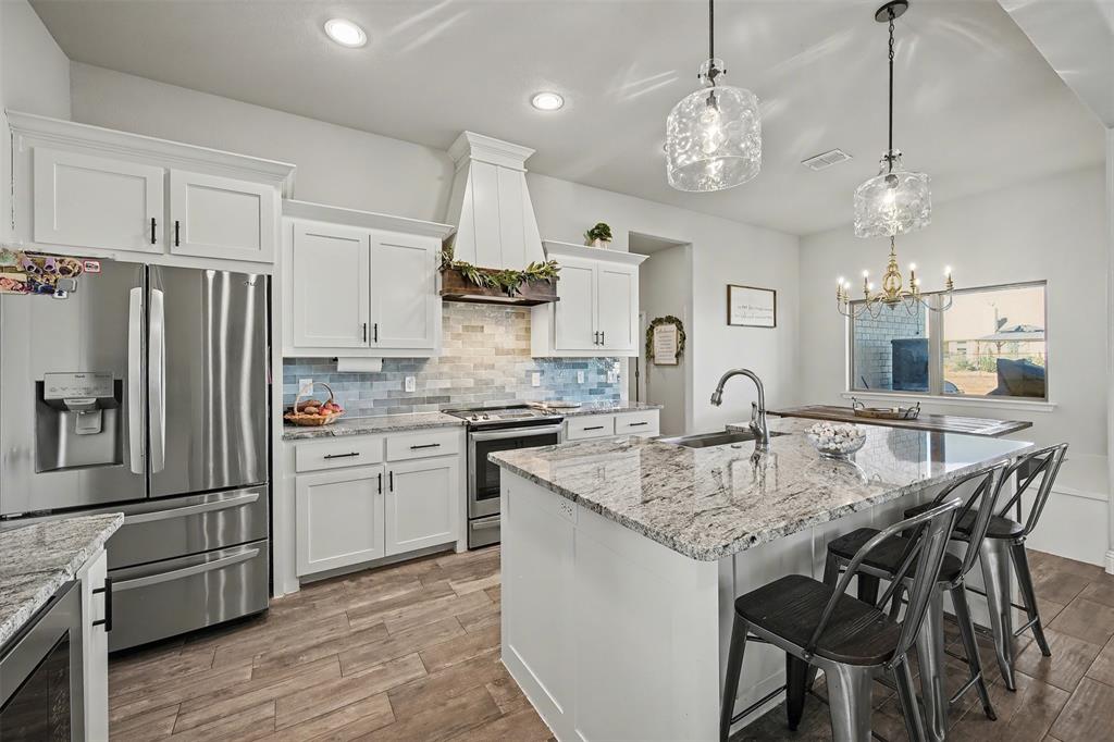 6334 Rustic Edge Street Godley, TX 76044 - Photo 9 of 26 a kitchen with stainless steel appliances granite countertop a kitchen island a stove a table and chairs in it