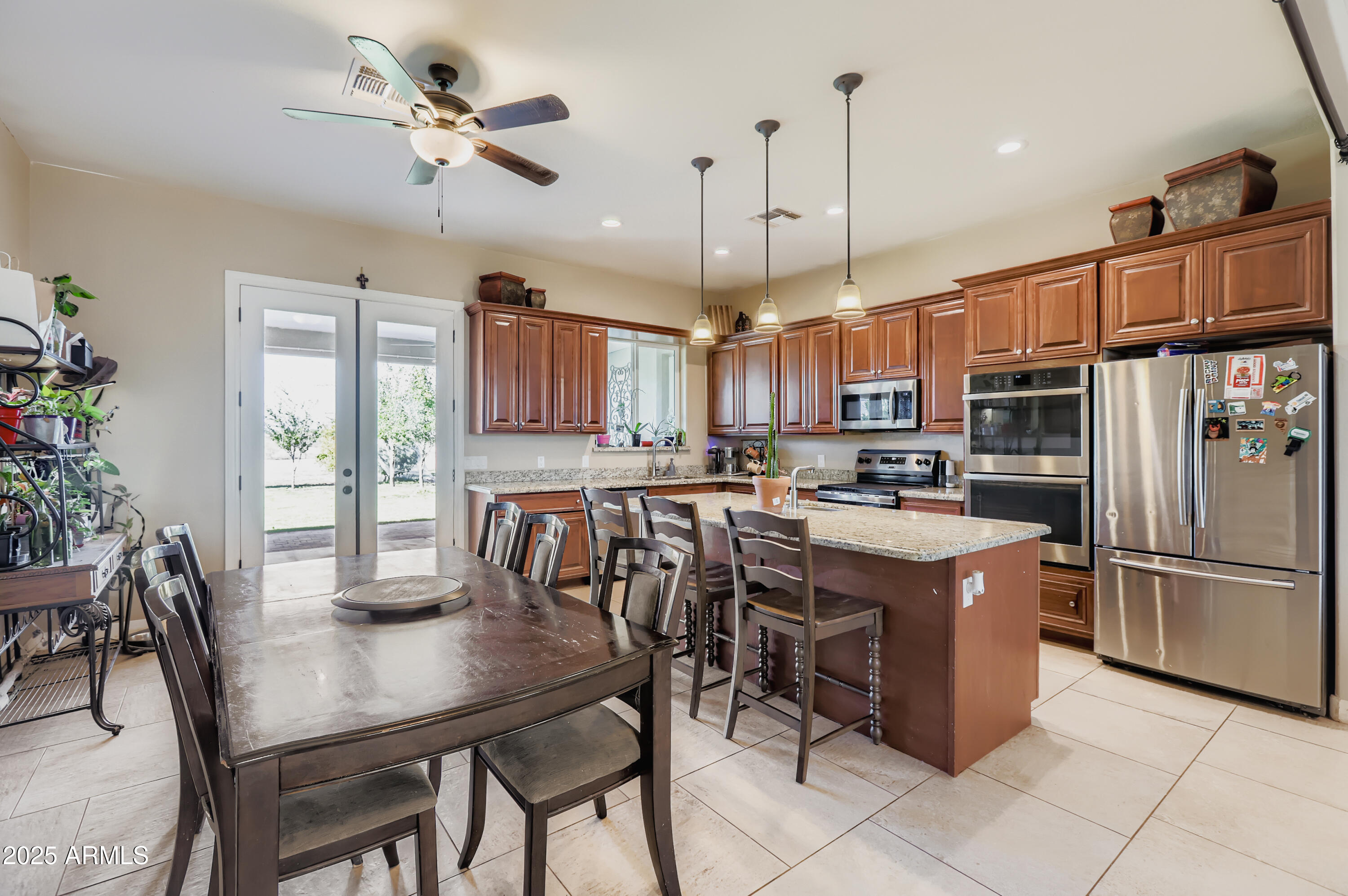22136 West Gambit Trail Wittmann, AZ 85361 - Photo 7 of 38 a kitchen with stainless steel appliances granite countertop a table chairs and a refrigerator