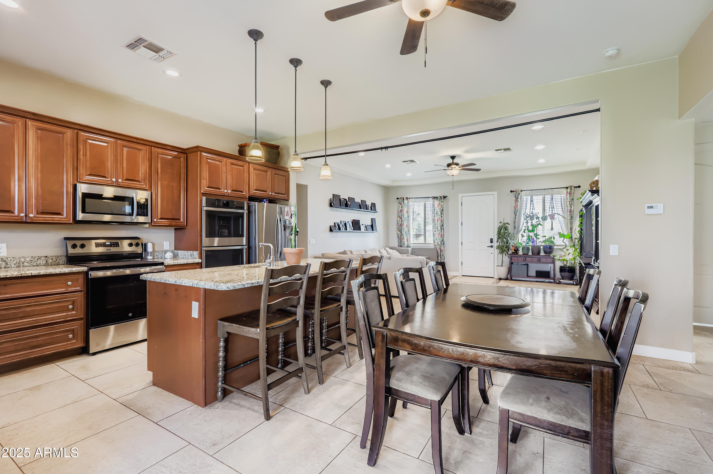 22136 West Gambit Trail Wittmann, AZ 85361 - Photo 9 of 38 a kitchen with stainless steel appliances kitchen island granite countertop a stove a refrigerator a kitchen island a dining table and chairs with wooden floor
