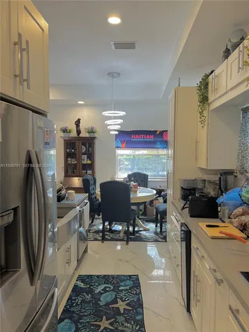 a kitchen with stainless steel appliances granite countertop a stove a refrigerator a sink a dining table and chairs