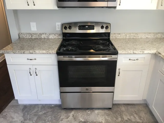 a kitchen with granite countertop white cabinets and black appliances