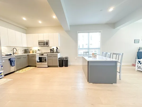 a large white kitchen with a stove a sink a microwave a counter top space and cabinets