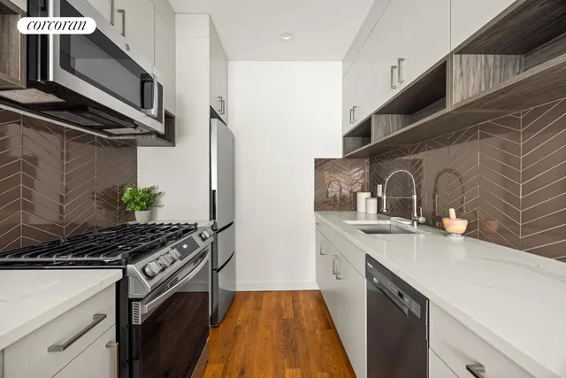 a kitchen with stainless steel appliances a stove a sink and a white wooden cabinets