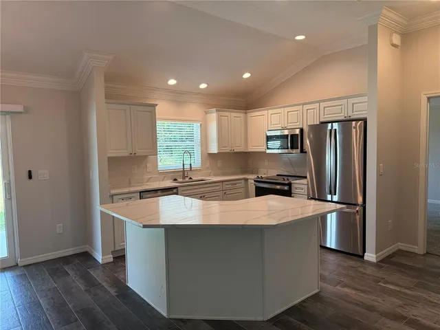 a large kitchen with stainless steel appliances granite countertop a sink a refrigerator and a stove