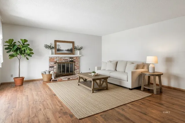 a view of an empty room with wooden floor and a fireplace