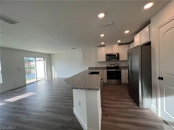 a kitchen with granite countertop wooden floors and wide window