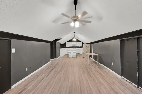 a view of a room with a chandelier fan and wooden floor
